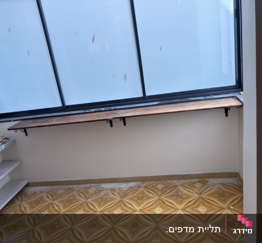 מדף עץ מותקן ליד חלון עם רצפת אריחים דקורטיבית